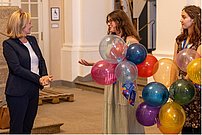 Drei stehende Personen mit Luftballons